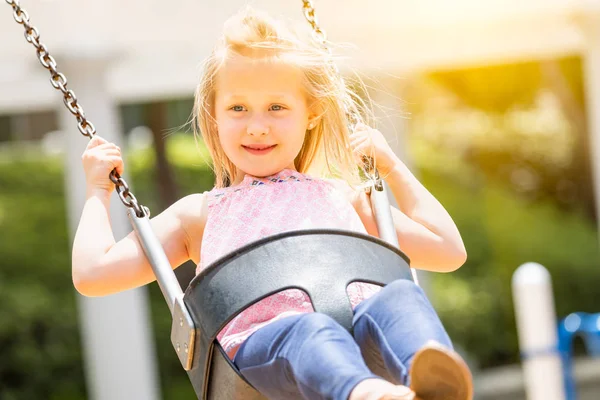 Bella ragazza si diverte sulle altalene al parco giochi — Foto Stock