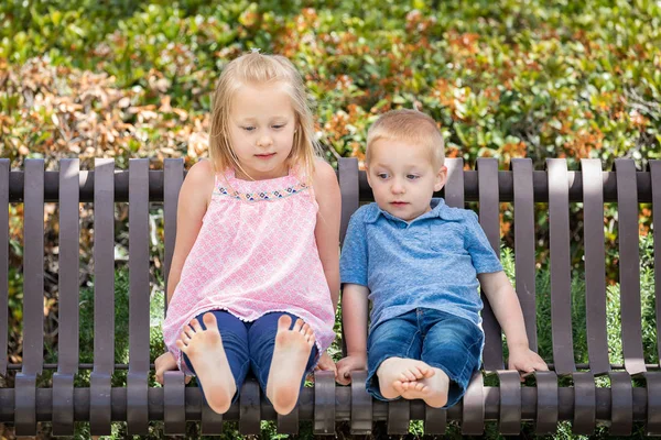 Młoda siostra i brat, zabawy na ławce w parku — Zdjęcie stockowe