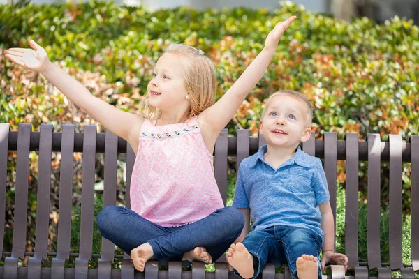 Genç kız ve erkek kardeş parkta bankta eğleniyor — Stok fotoğraf
