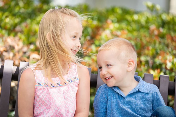 Giovane sorella e fratello having divertimento su il panchina a il parco — Foto Stock