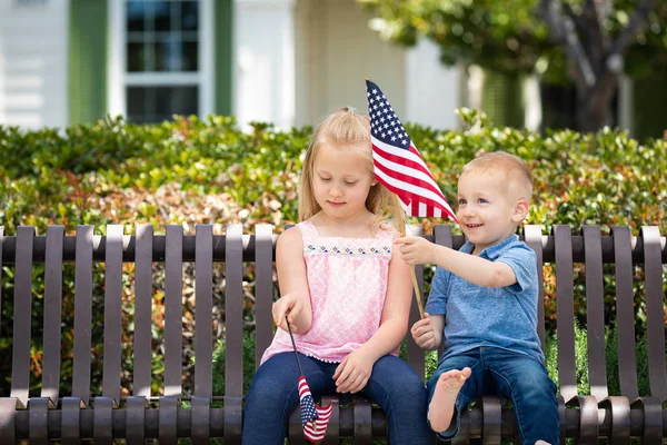 Fiatal testvérpár összehasonlítása egymás amerikai zászló mérete a parkban a padon. — Stock Fotó