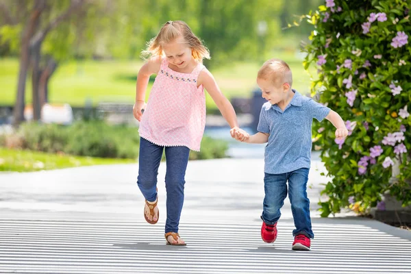 Kleine Schwester und Bruder halten Händchen und rennen im Park — Stockfoto