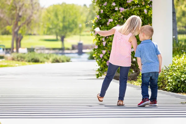 Kleine Schwester und Bruder halten Händchen und gehen im Park spazieren — Stockfoto