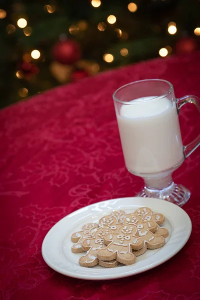 Gingerman Cookes On Plate with Milk In Front Decorated Lit Tree. — Stock Photo, Image