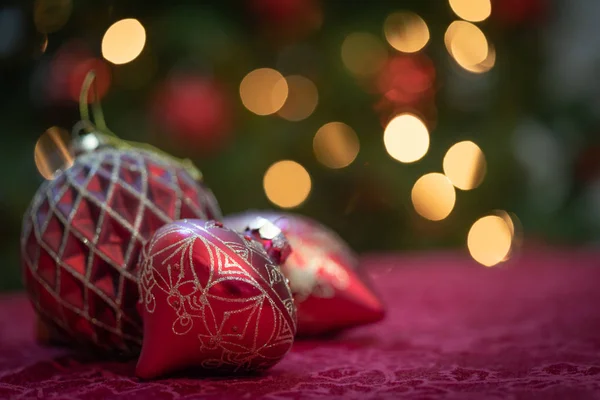 Aufwendiger Weihnachtsschmuck ruht auf Tisch vor beleuchtetem Baum — Stockfoto