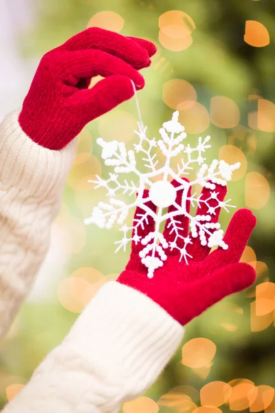 Mulher vestindo luvas vermelhas sazonais segurando branco floco de neve ornamento de Natal . — Fotografia de Stock