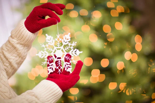 Mulher vestindo luvas vermelhas sazonais segurando branco floco de neve ornamento de Natal . — Fotografia de Stock