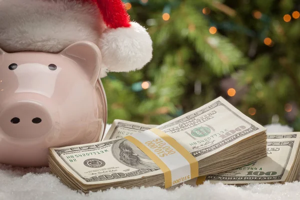Piggy Bank Wearing Santa Hat Near Stacks of Hundred Dollar Bills on Snowflakes — Stock Photo, Image