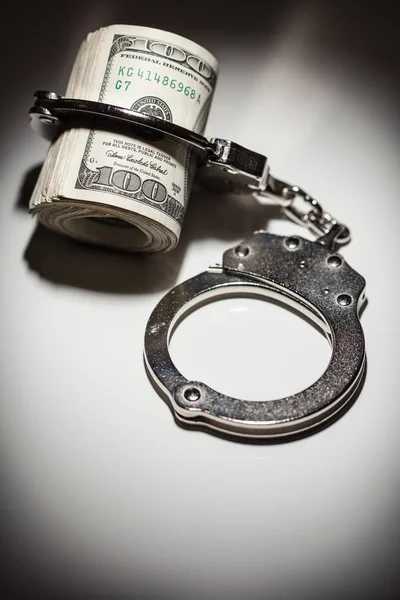 Handcuffs Locked on Roll of One Hundred Dollar Bills Under Spotlight — Stock Photo, Image