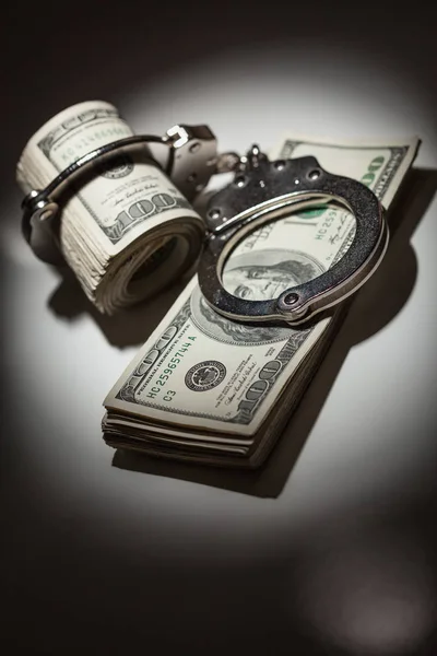 Handcuffs Locked on Roll of One Hundred Dollar Bills Under Spotlight — Stock Photo, Image