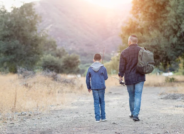 Karışık ırk babası ve oğlu dışarıda oltayla yürüyor. — Stok fotoğraf