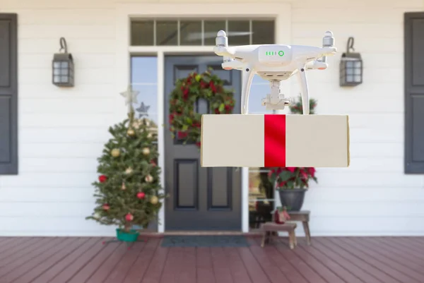 Drone Delivering Wrapped Package with Red Ribbon to Christmas Decorated House Porch — Stock Photo, Image