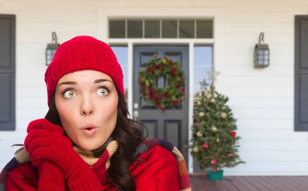 Junges Mädchen mit Schal, roter Mütze und Handschuhen steht auf weihnachtlich dekorierter Veranda — Stockfoto