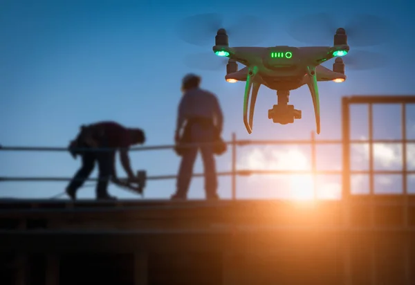 Silueta del dron del sistema de aviones no tripulados (UAV) Quadcopter Drone en el aire sobre el edificio en construcción —  Fotos de Stock