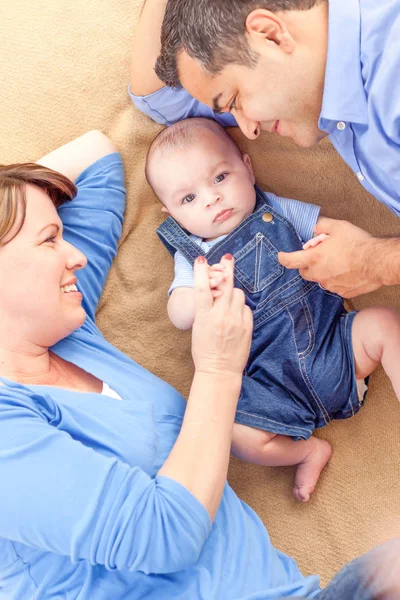 Young Mixed Race Couple Laying With Their Infant On A Blanket — Stock Photo, Image