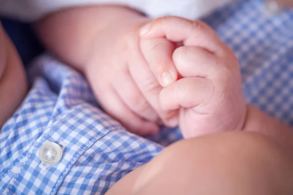 Primer plano de las manos del bebé mientras está acostado en la vuelta de la madre —  Fotos de Stock