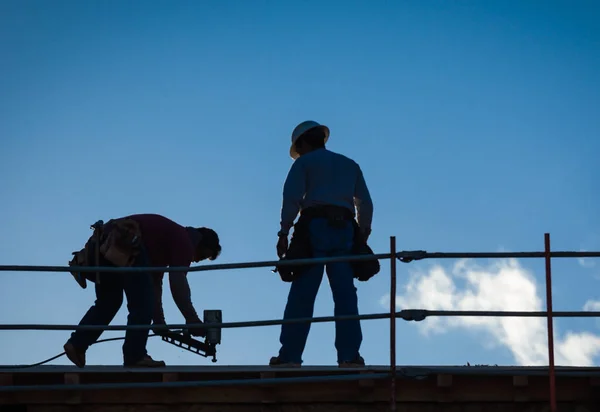 Silueta de los trabajadores de la construcción en el techo del edificio . — Foto de Stock