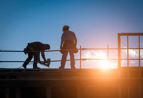 Bouw werknemers silhouet op dak van gebouw. — Stockfoto