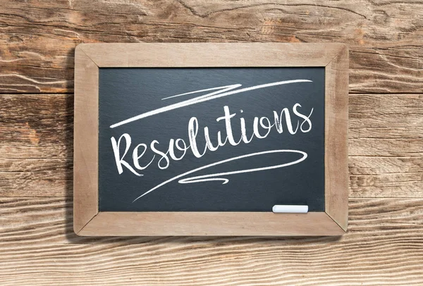 Resolutions Written on Slate Chalk Board Against Aged Wood Background — 스톡 사진