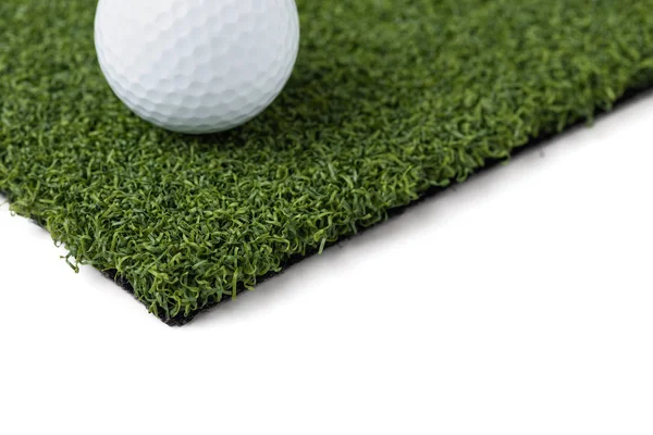Bola de golfe descansando na seção de grama relva artificial em fundo branco — Fotografia de Stock