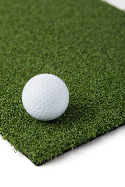 Balle de golf reposant sur la section de gazon artificiel sur fond blanc — Photo