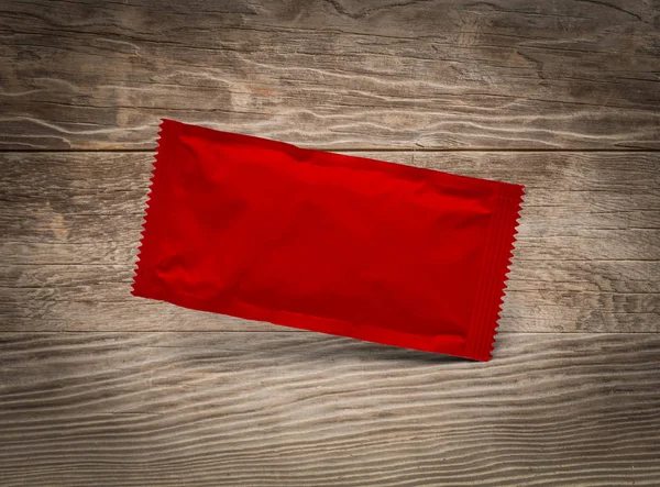 Paquete de condimento rojo en blanco flotando sobre fondo de madera envejecida —  Fotos de Stock