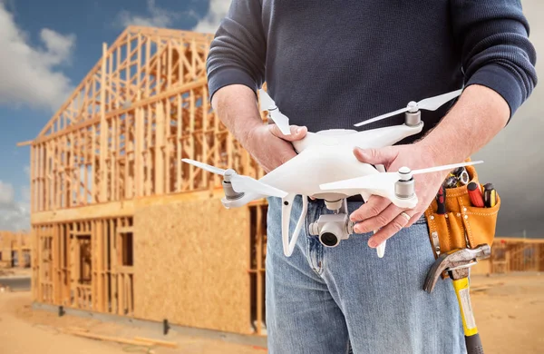 Bauarbeiter und Drohnenpilot mit Werkzeuggurt hält Drohne auf Baustelle — Stockfoto