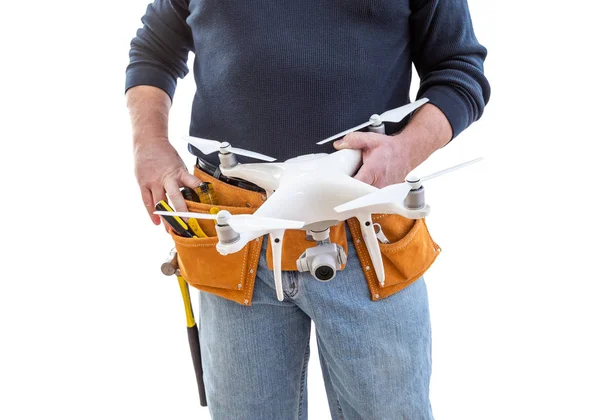 Εργάτης οικοδομών και χειριστής δρομέων με τη ζώνη εργαλείων που κρατά το κτύπημα quadcopter απομονωμένο στο άσπρο υπόβαθρο — Φωτογραφία Αρχείου