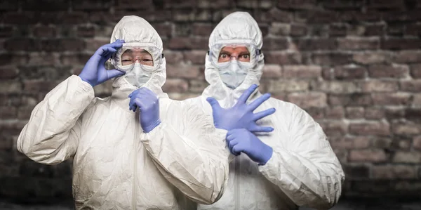 Chinese and Caucasian Men Wearing Hazmat Suit, Goggles and Mask with Brick Wall Background — Stock Photo, Image