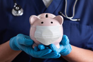 Doktor ya da Hemşire Eldiven Giyiyor Domuzcuk Kumbarası Giyiyor Tıbbi Maske Giyiyor.