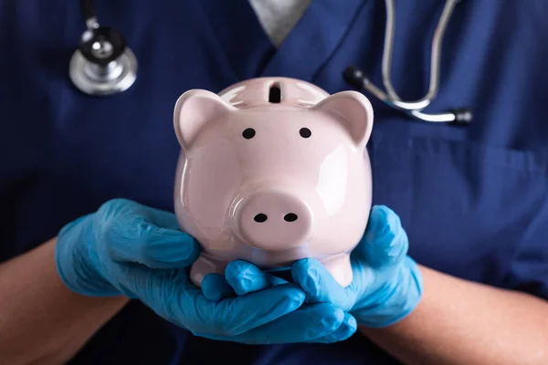 Médico Enfermeira Vestindo Luvas Cirúrgicas Segurando Piggy Bank — Fotografia de Stock