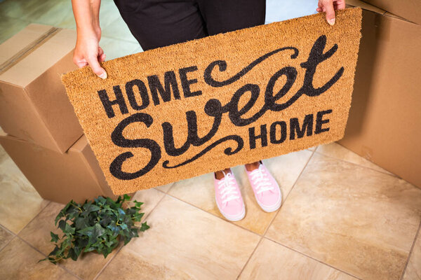 Woman in Pink Shoes Holding Home Sweet Home Welcome Mat, Boxes and Plant.