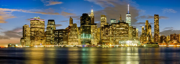 Sunset in New York City with a view of the East River and the illuminated skyline of Lower Manhattan