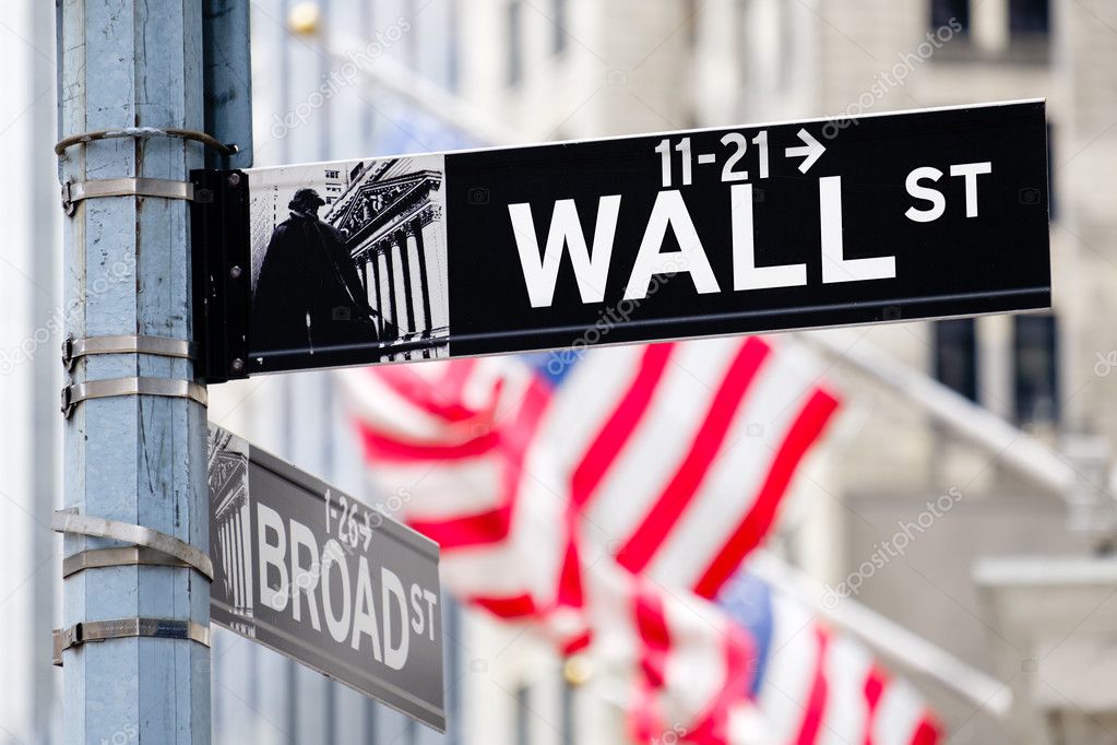 Wall street sign in New York City with american flags on the bac