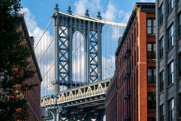 Famous view of the Manhattan Bridge and a Brooklyn street sidelined by old red brick buildings in New York City
