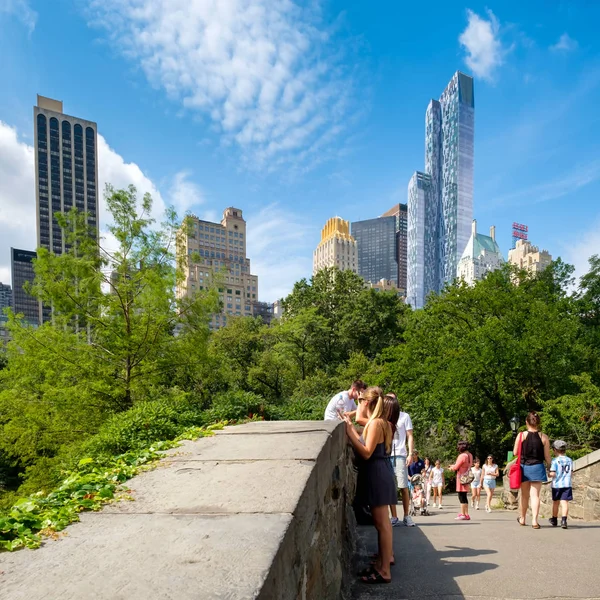 Gente en un puente de piedra en Central Park con rascacielos de Nueva York — Foto de Stock