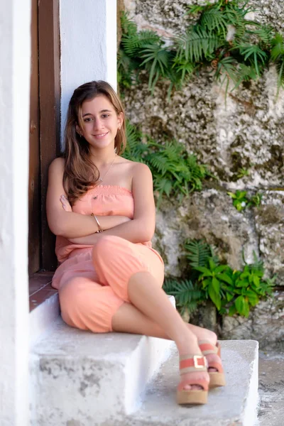 Adolescente hispana sentada en una vieja puerta con una pared de piedra como —  Fotos de Stock