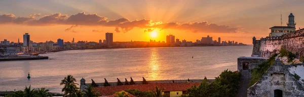 Západ slunce v Havaně s slunce nad budovami a el Morro hrad na popředí — Stock fotografie