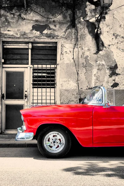 Red vintage car next to a black and white building in Old Havana