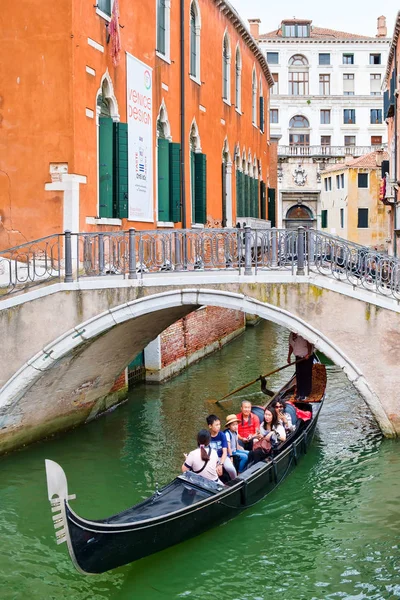 Gondel, die Touristen unter einer Brücke auf einem schmalen Kanal in Venedig transportiert — Stockfoto