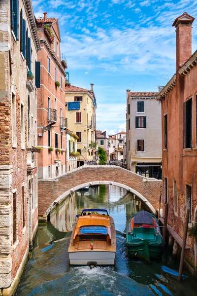 Boot unter einer Brücke auf einem schmalen Kanal, umgeben von alten Gebäuden in Venedig — Stockfoto