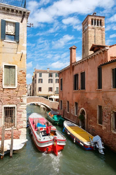 Boot unter einer Brücke auf einem schmalen Kanal, umgeben von alten Gebäuden — Stockfoto