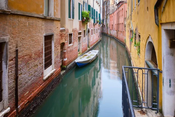 Small boat on a narrow canal surrounded by old weathered buildings in Venice — Stock Photo, Image
