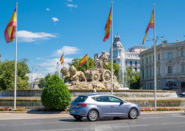 The Cibeles Square in Madrid with the famous fountains and spanish flags clipart