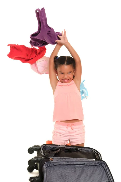 Menina pequena jogando roupas de uma mala para o ar - Isolado em branco — Fotografia de Stock