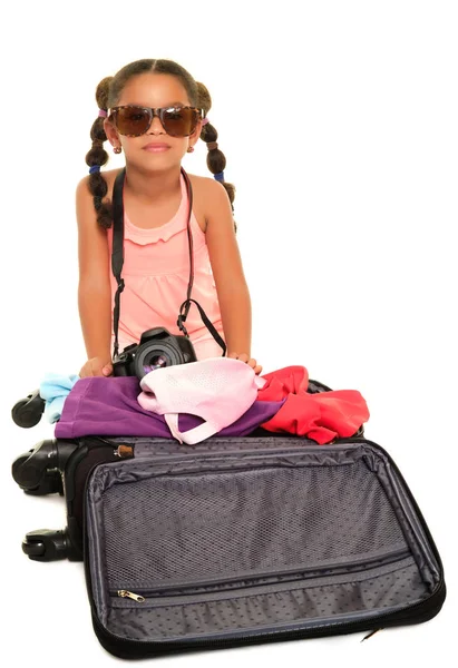 Liten flicka med solglasögon och en kamera som öppna en resa resväska - isolerad på vit — Stockfoto