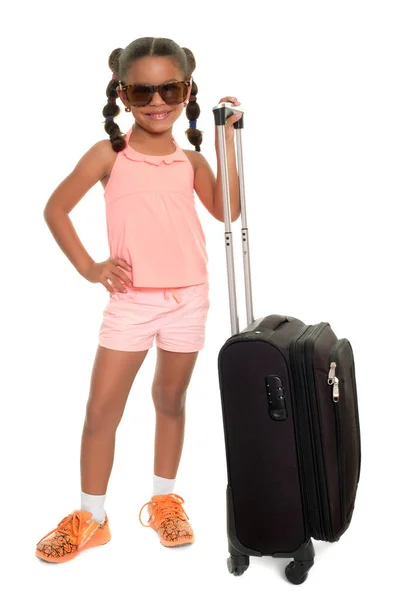 Милая многорасовая маленькая девочка с чемоданом для путешествий и улыбкой — стоковое фото