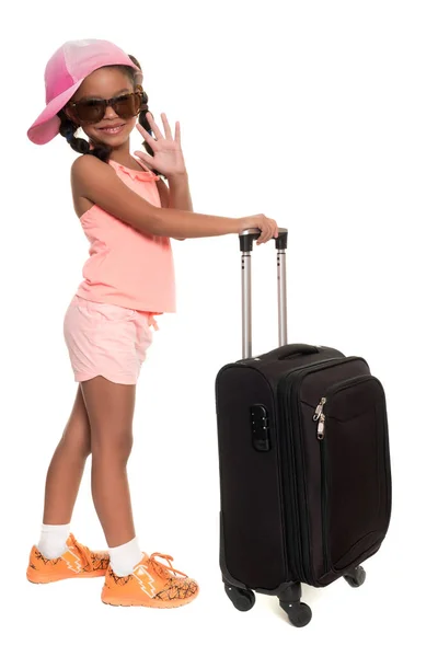 Menina afro-americana bonito carregando uma mala de viagem e acenando adeus — Fotografia de Stock