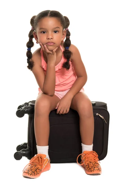 Χαριτωμένο αφρικανική αμερικανική κορίτσι που κάθεται σε μια βαλίτσα ταξιδίου που αναζητούν βαρεθεί και ανυπόμονος — Φωτογραφία Αρχείου