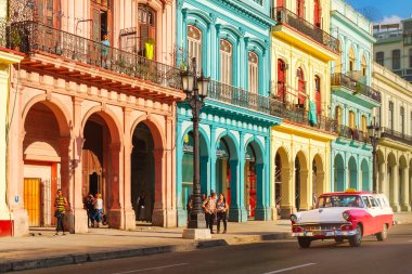 Classic old cars and colorful buildings in downtown Havana clipart